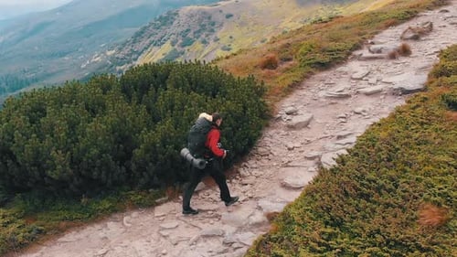 Aerial View of a Traveler Photographer with Backpack Climbing By Mountain Range