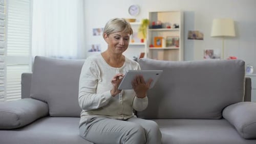 Mature Woman Using Tablet on Sofa at Home