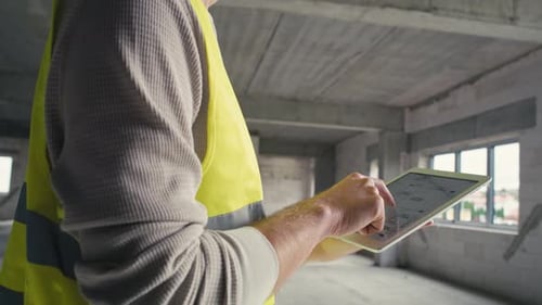 Low angle footage of caucasian engineer browsing building project on a digital tablet.