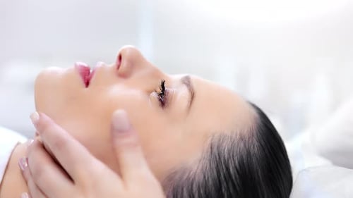 Closeup Smiling and Relaxing Beautiful Female Face During Massaging Spa Procedure Side View