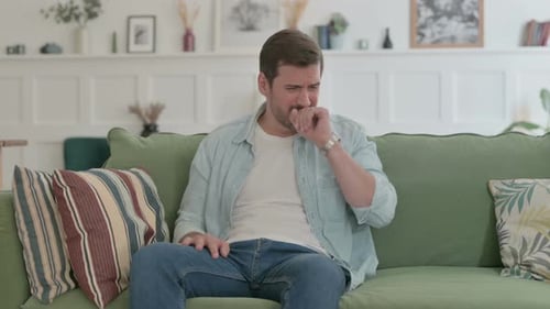 Young Man Coughing While Sitting on Sofa
