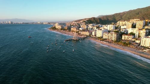 wide aerial of Puerto Vallarta ocean coastal skyline at sunset with boats anchored at a pier in Mexi