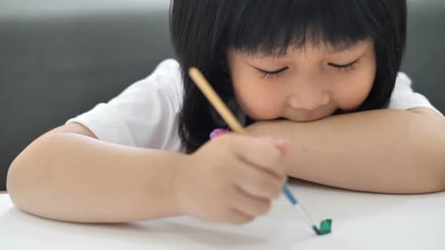 Close up happy Asian girl drawing picture with water color on paper.
