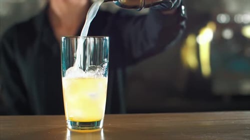 Bartender Pouring Refreshing Yellow Cocktail at the Bar