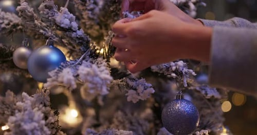 Decorating Snowy Christmas Tree With Silver Ornaments
