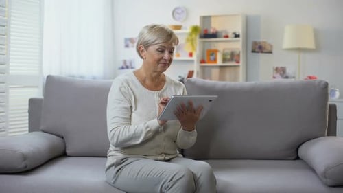 Senior Woman Using Tablet at Home on Couch
