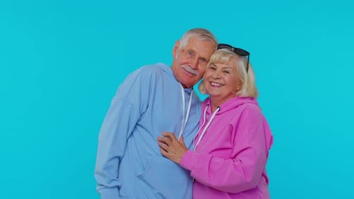 Senior Couple Embracing Tenderly in Front of Turquoise Backdrop