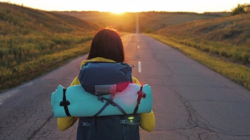 Woman Walks Down Rural Road Toward Golden Sunrise