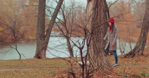 Little Puppy Walks with the Mistress. Girl Walking a Dog on a Leash, a Walk in the Park in the Fall