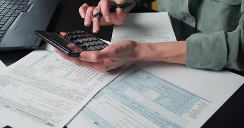 Hands Calculate Taxes with Form and Calculator