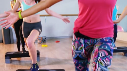 Women Doing Step Aerobics in Bright Fitness Studio