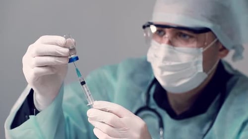 Medical Professional Drawing Liquid Into Syringe