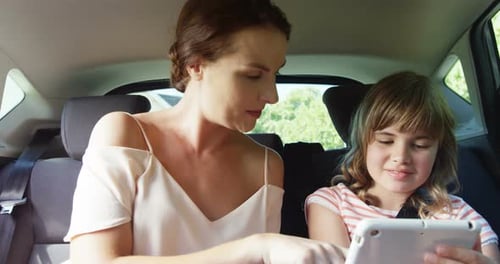 Mother and Daughter Using Tablet in Car