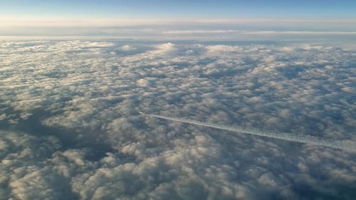 Incredible view from the cockpit of an airplane flying high above the clouds leaving a long white co