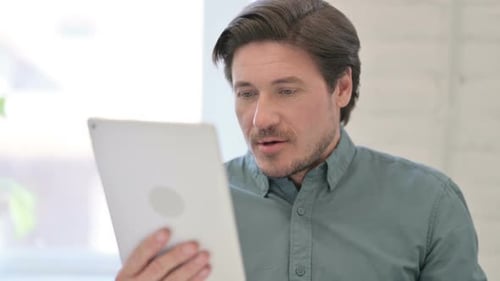 Adult Man Reacts Positively to Tablet Indoors