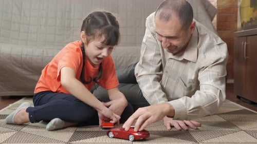 Father and Daughter Playing with Toy Cars Indoors