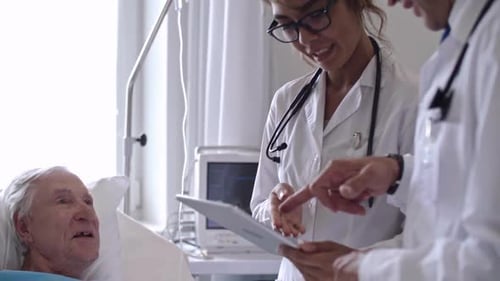 Doctors Reviewing Senior Patient's Chart in Hospital Room