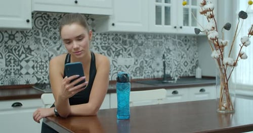 Young Woman Using Phone in Bright Kitchen