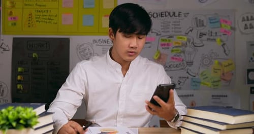 Young Man Answers Phone at His Office Desk