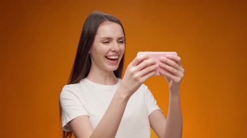 Young Woman Playing Games on Her Smartphone in Studio