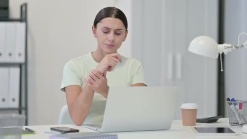 Young Adult Woman Massaging Sore Wrist at Desk