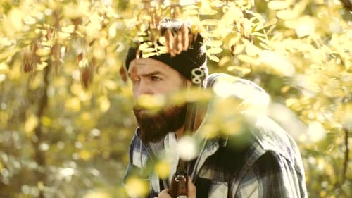 Bearded Man Holding a Rifle in a Wooded Area