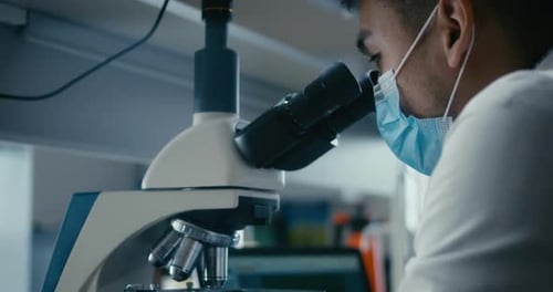 Scientist Studying Sample in Microscope