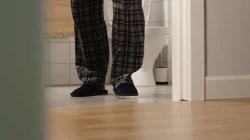 Man Walks into Bathroom Wearing Pajamas and Slippers