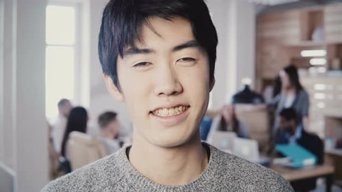 Close-up Portrait of Successful Asian Male Creative Manager Smiling at Modern Office. Handsome Man