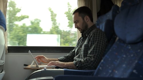 Hübscher Mann, der digitales Tablet benutzt, während er im Zug reist.