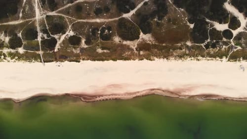 AERIAL: Panning Shot of a Beach and Coastline of a Calm Green Color Sea