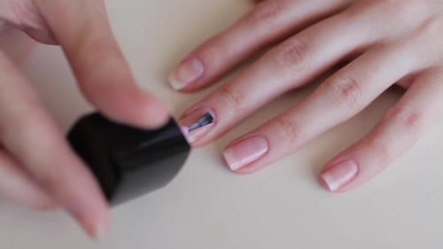 Woman Applying Pale Nail Polish, Close Up