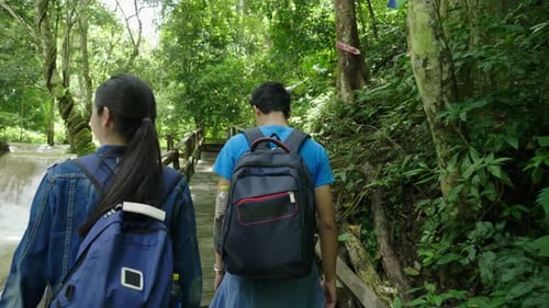 Couple Hiking Tropical Trail Alongside Lush Waterfall