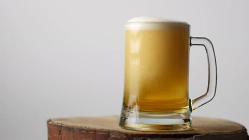 Beer Pouring Into Glass Mug on Wood