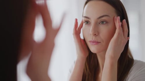 Mujer que examina la piel perfecta cerca del espejo