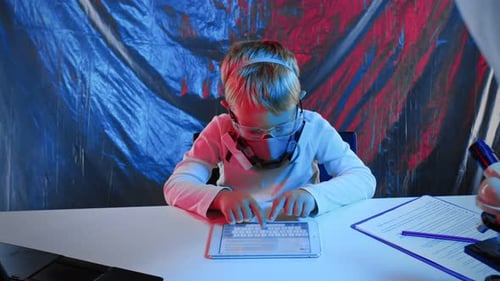 Ein kleiner Junge mit Schutzmaske arbeitet mit einem Tablet, während er in einem Labor an einem Tisch sitzt