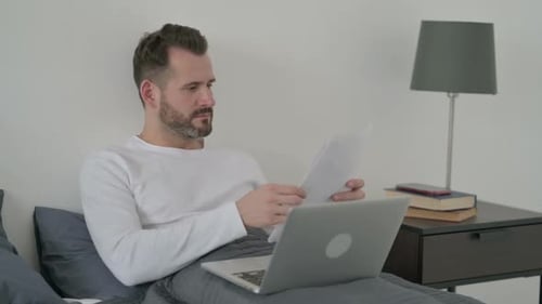 Man Working On Laptop From Bed