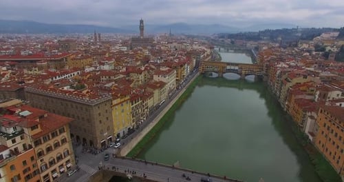 Italy. Florence. Overcast Day. Flight Over the River Arno. Ponte Vecchio Bridge and Palazzo Vecchio