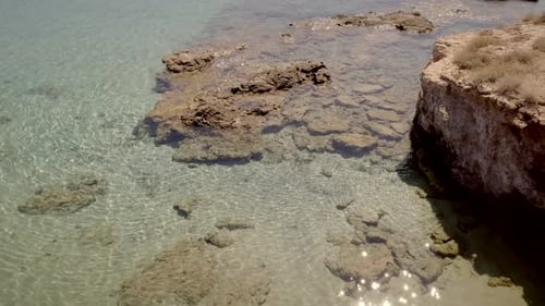 Aerial view of beach shore with rocks and very calm water in Greece.