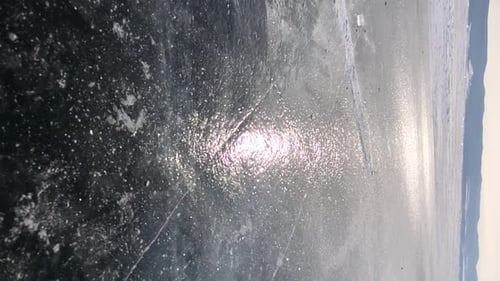 A Piece of Transparent Ice Breaks on the Surface of Lake Baikal and Crumbles Into Small Fragments in