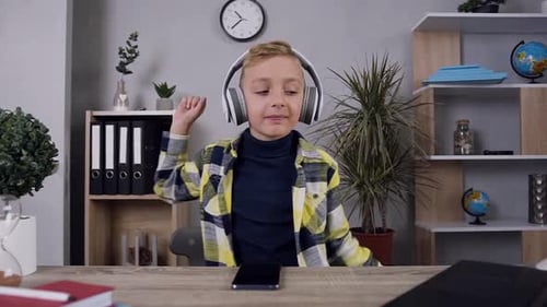 Teen Blond Fröhlicher Junge im stilvollen Hemd, der unter moderner Musik in seinen Kopfhörern tanzt