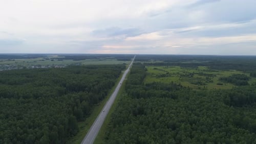 Drone aerial shot of a trucks and cars on the summer forest road near hills. Evening 09