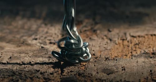 Metal Chain Falling onto Cracked Brown Surface