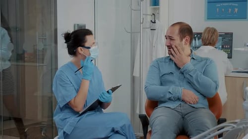 Man with Toothache Talking to Dentist in Clinic