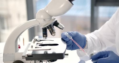 Scientist Adding Sample to Microscope Slide in Lab