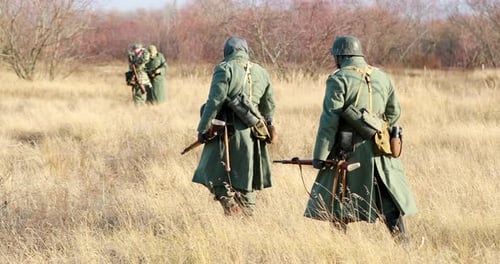 Reenactors Dressed As German Infantry Soldiers In World War II Marching Walking Along Meadow In Cold