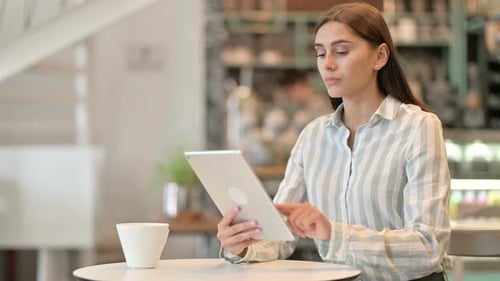 Serious Professional Young Latin Woman Using Tablet in Cafe