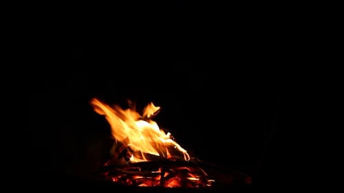 Brennendes Lagerfeuer aus Brennholz auf schwarzem Hintergrund mit glänzenden Funken