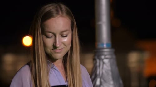 Young Woman Using Smartphone in City at Night