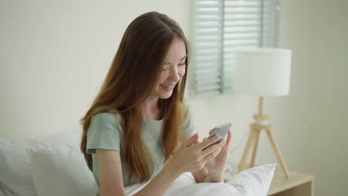 Woman Using Mobile Phone in Bedroom